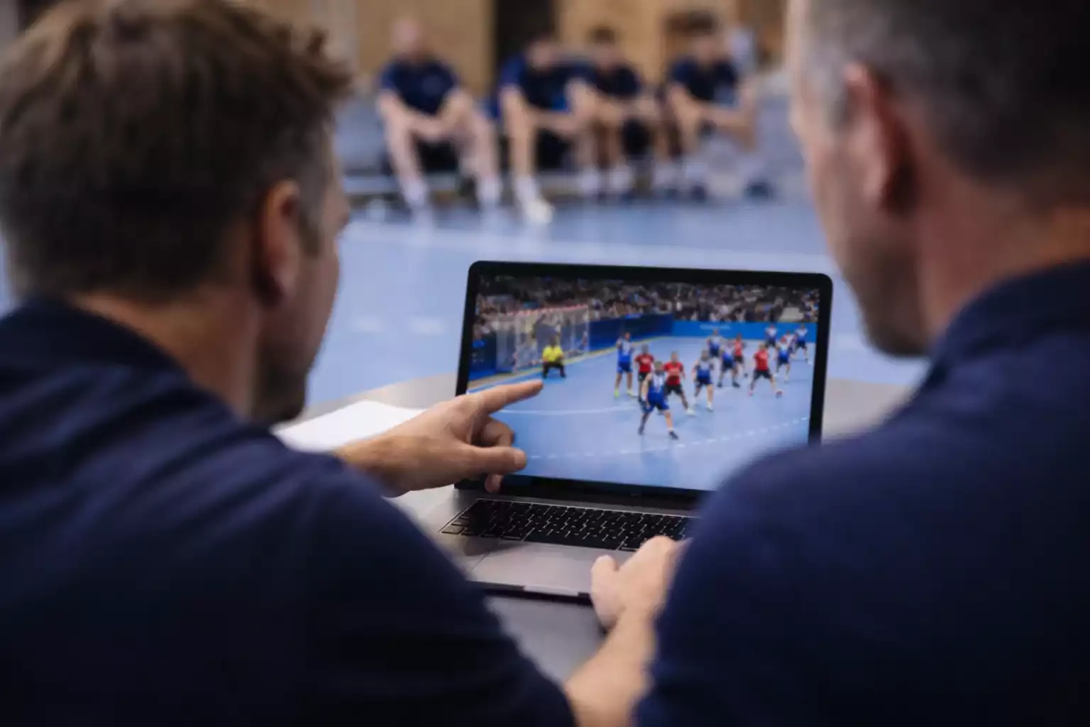 Trainer analysiert Spielszenen am Laptop mit seinem Team